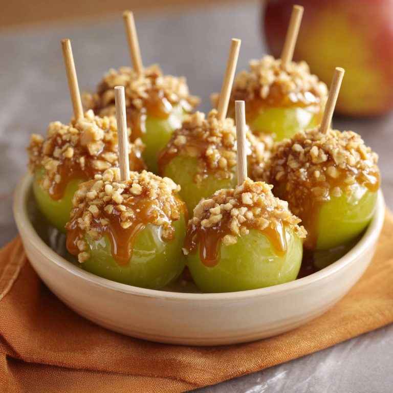 Knackige Karamell-Äpfel, serviert in einer Schale, zeigen eine Nahaufnahme des glänzenden Karamells und der knackigen Erdnuss-Toppings.
