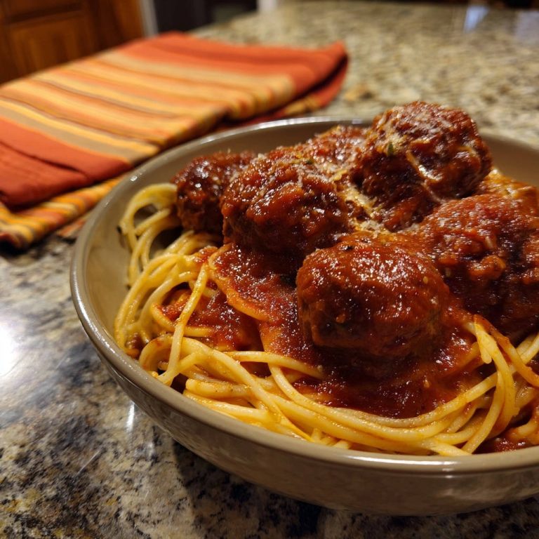 Spaghetti mit herzhaften Fleischbällchen in einer Nahaufnahme, serviert in einer rustikalen Schüssel, mit reichlich Soße und Parmesan.
