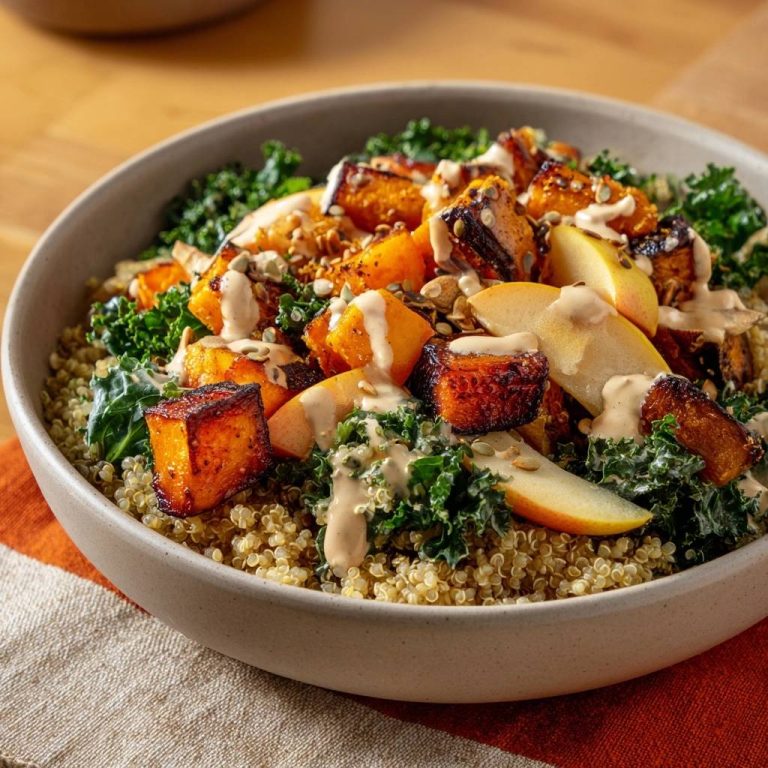 Knuspriger Kürbis-Quinoa-Bowl mit Kale und Apfel in einer Schüssel, serviert aus der Vogelperspektive, mit cremigen Dressing.