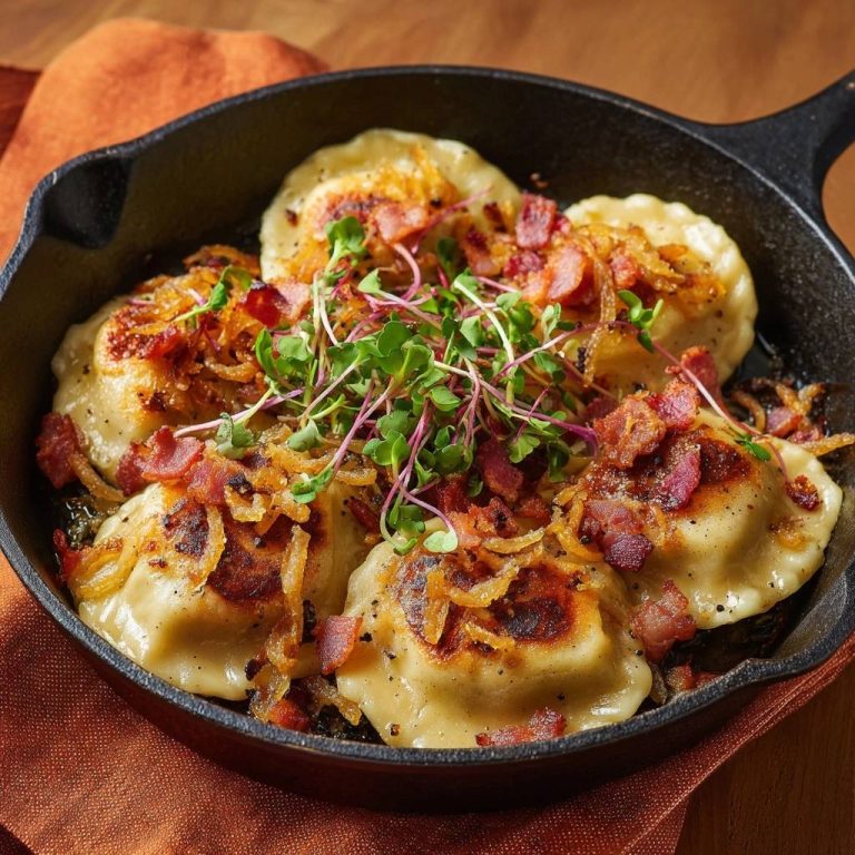 Knusprige Pfannen-Pierogi mit Räuchertofu und Zwiebeln, serviert in einer gusseisernen Pfanne, garniert mit frischen Sprossen und knusprigem Speck.