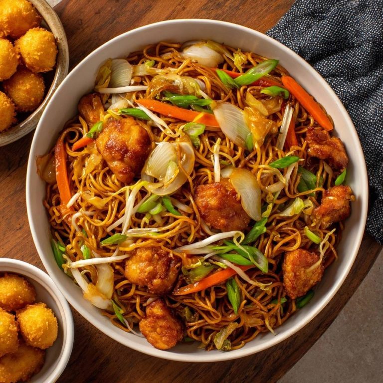 Hähnchen-Chow-Mein mit knusprigen Chicken Balls, serviert in einer großen weißen Schüssel mit Gemüse und Nudeln, aus der Vogelperspektive.