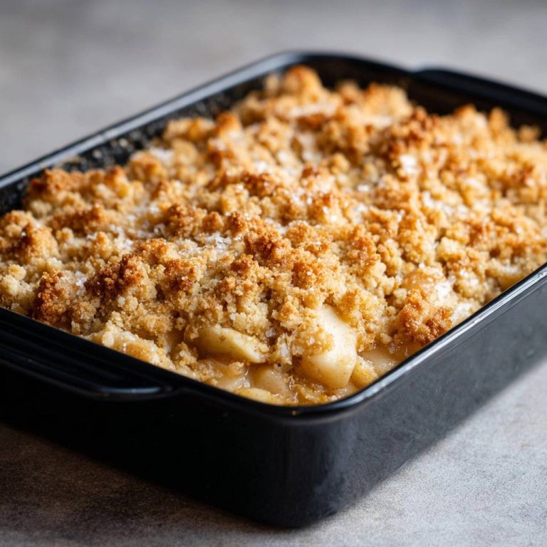 Knuspriger Apfel-Crumble in einer schwarzen Auflaufform, eine Nahaufnahme der goldbraunen Streusel und der fruchtigen Füllung.