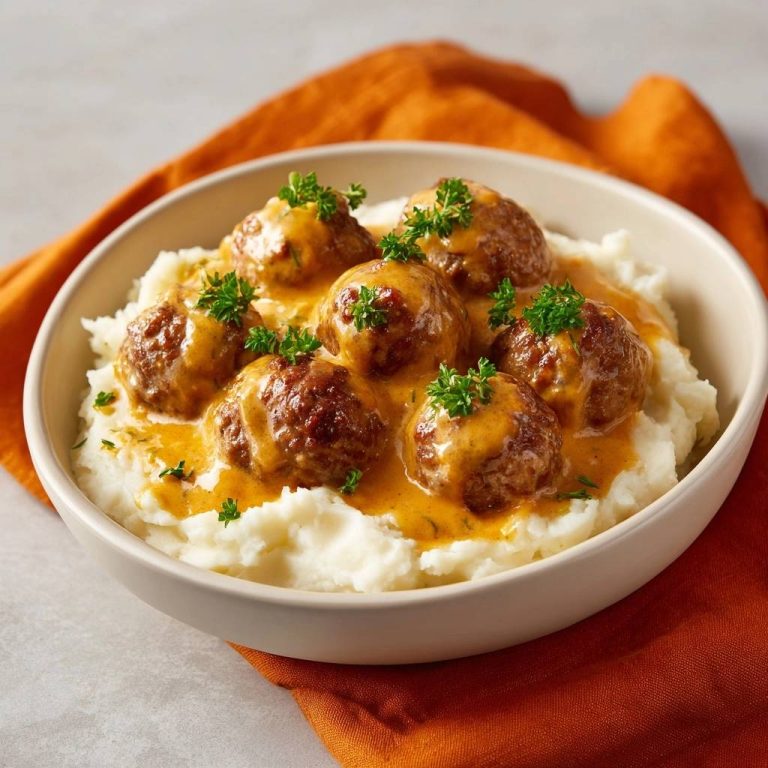 Schwedische Fleischbällchen mit Sahnesauce und Kartoffelpüree serviert in einer cremigen Schüssel, garniert mit frischer Petersilie.