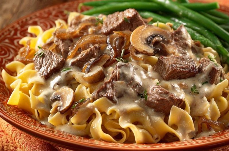 Cremiges Rindfleisch mit Pilzen über breiten Nudeln