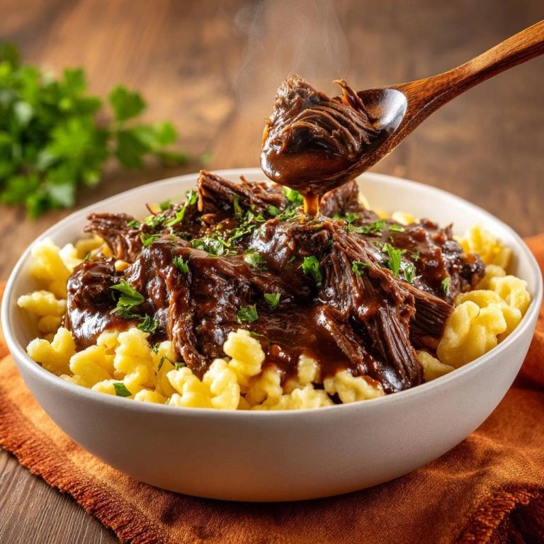 Butterzartes Rindergulasch mit Spätzle, serviert in einer Schüssel, mit einem Löffel, von dem köstlicher Gulasch tropft.