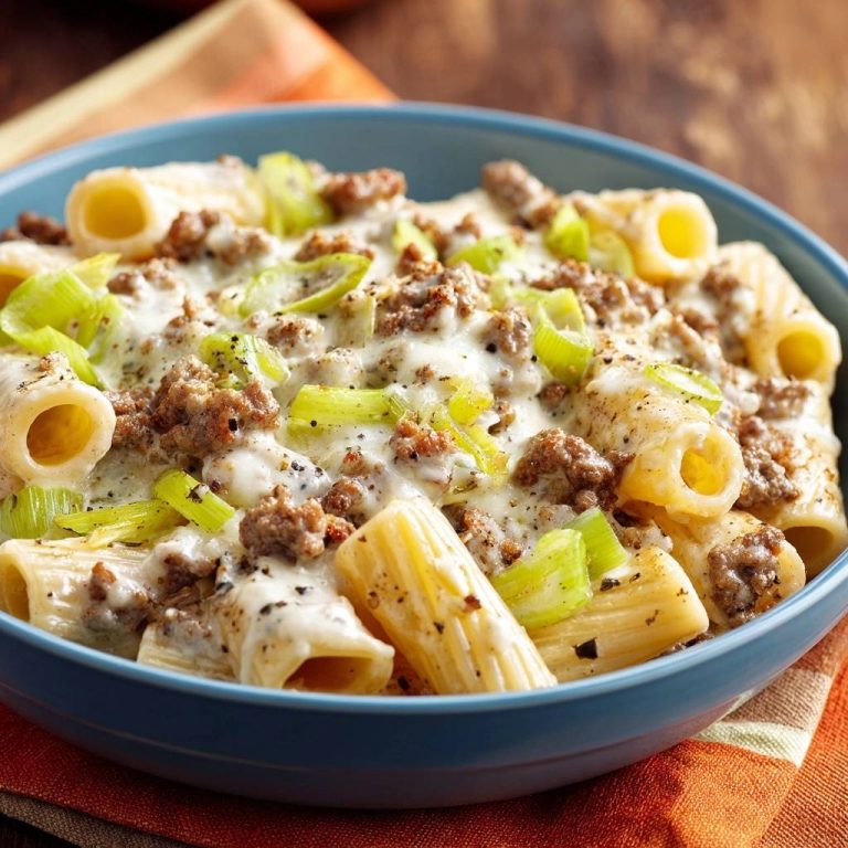 Cremige Rigatoni mit Hackfleisch und Lauch, serviert in einer blauen Schüssel, zeigt die cremige Sauce und die gebröselten Fleischstücke von oben.