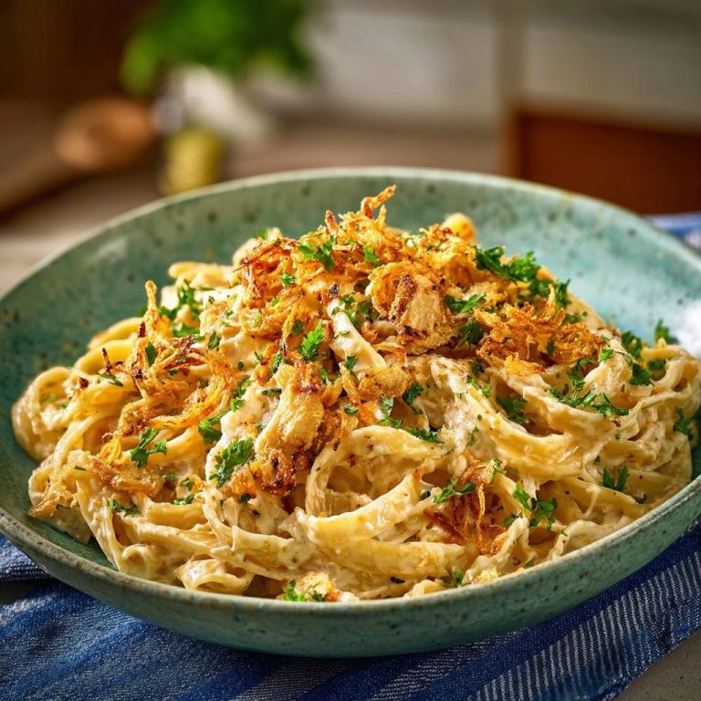 Cremige Tagliatelle mit knusprigem Knoblauch in einer Schüssel, garniert mit frischer Petersilie und knusprigen Knoblauchstückchen.