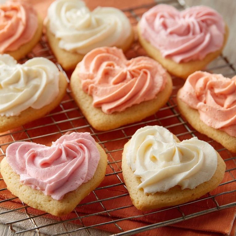 Herz-Butterplätzchen mit Frosting, frisch gebacken und auf einem Kühlgitter platziert, bereit zum Genießen. Die herrlich dekorierten Kekse verströmen einen unwiderstehlichen Duft.