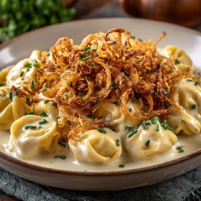 Cremige Tortellini mit Röstzwiebeln, garniert mit frischen Schnittlauchstückchen und cremiger Sauce.