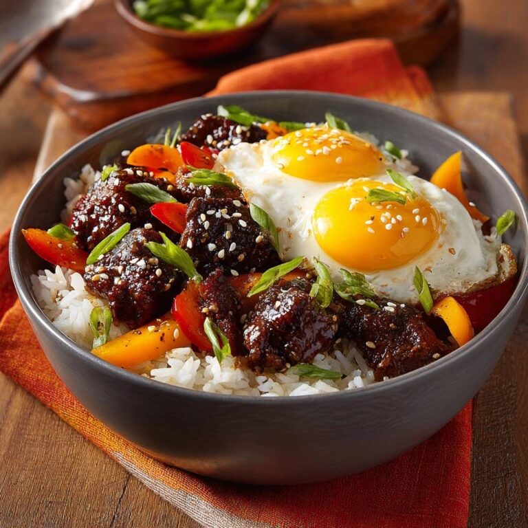 Herzhaftes Rindfleisch-Stir-Fry mit Spiegelei serviert in einer Schüssel, garniert mit frischen Kräutern und Sesamkörnern, eine köstliche Mahlzeit.